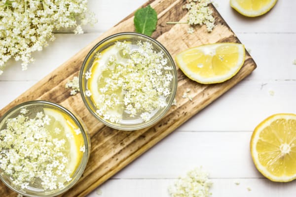 elderflower in a glass with lemon slices and lemon wedges