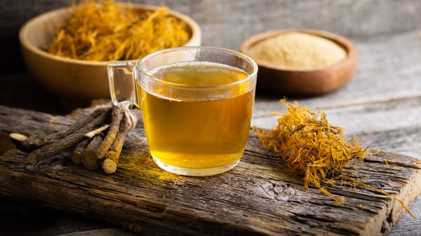 Glass cup of licorice tea with licorice root and fiber on rustic background, alternative medicine ( glycyrrhiza glabra )