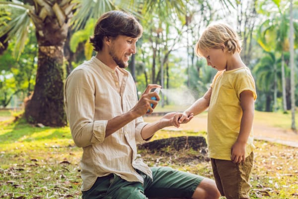 Dad sprays his son with natural bug repellent. Peppermint oil for bugs.